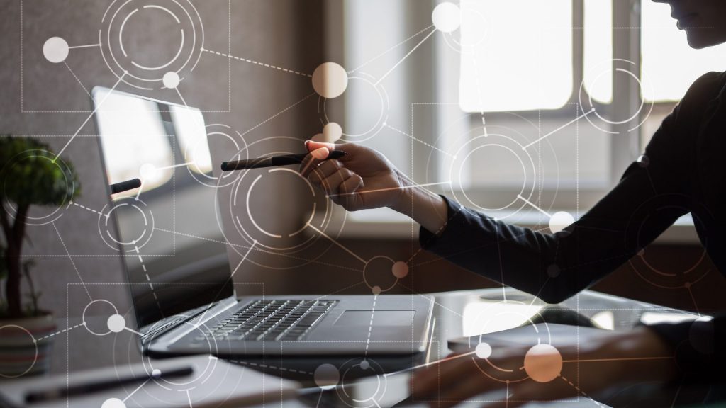 Laptop on the table with hand pointing at the Business Simulation Software