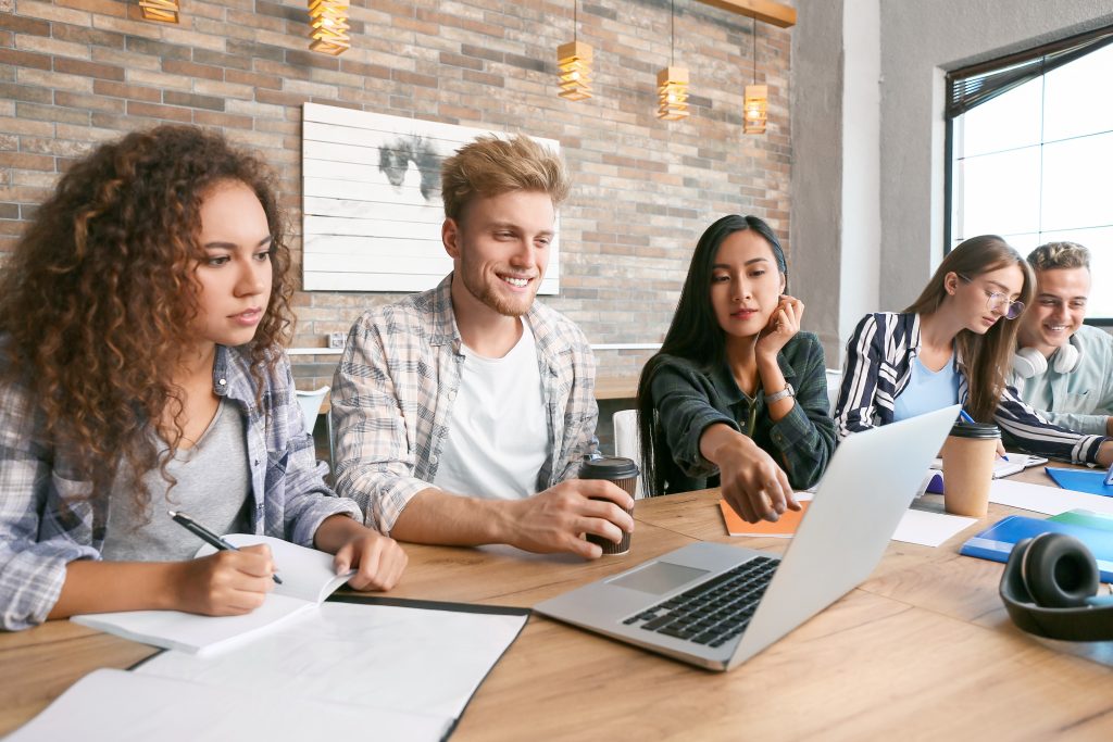 Students at a table engaging with a laptop.