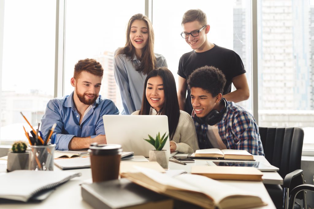 Absorbed diverse students looking at laptop and study together at college library