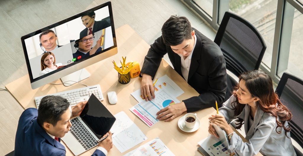 Business people around a table in a video conference.