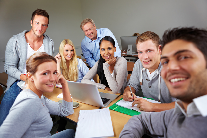 Students around a table smiling and using Experiential online learning software.