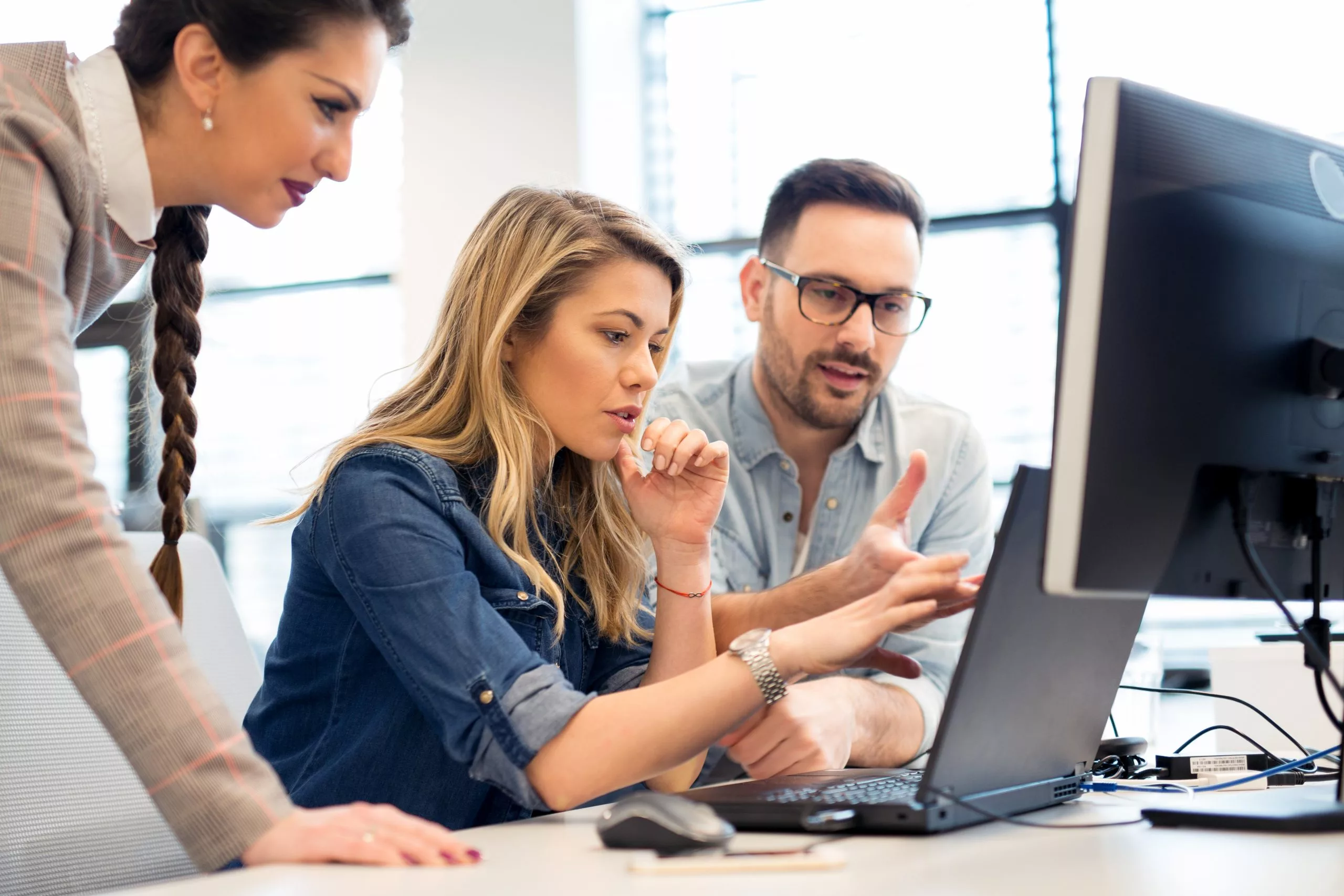 Three people using the business simulation, SimVenture Evolution, in the workplace for professional development purposes.