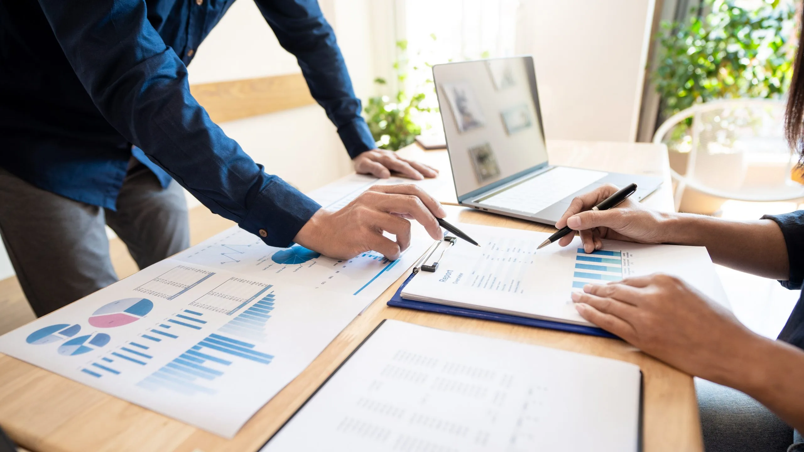 Two people looking at paper charts on table whilst analysing the results from playing the small business simulation SimVenture Classic