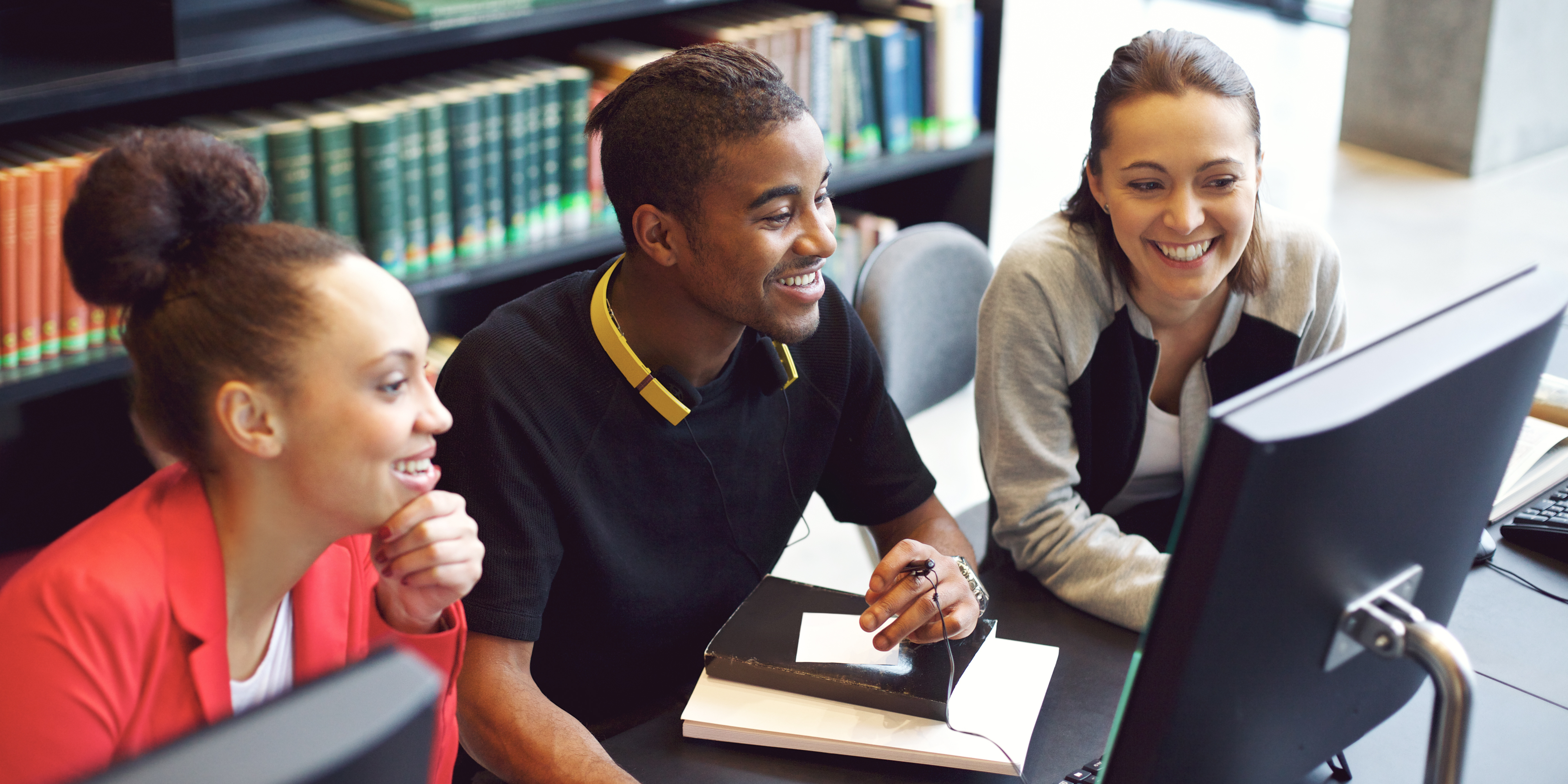 Three university students having fun learning while using business simulation, Evolution.