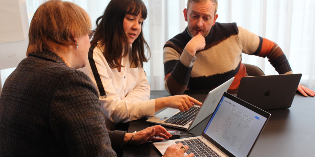 Three people with three laptops in front of them, all using the startup ideas platform, Validate. This shows hands-on learning in enterprise education.