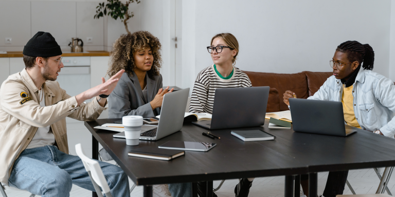 Four aspiring entrepreneurs sitting around a table using Validate to develop company startup ideas.